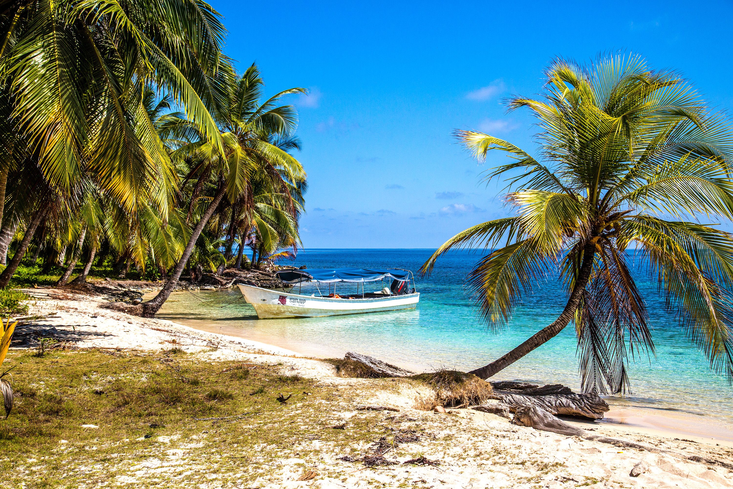 View of the ocean with a boat on the shore of a sandy beach.
