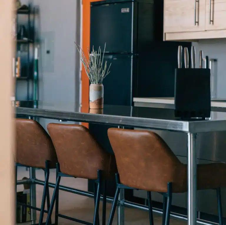 The metal kitchen island with brown leather high chairs at a Vrbo holiday rental property out in the desert in Terlingua, Texas