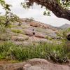 A hiker climbs rocks at Enchanted Rock State Natural Area