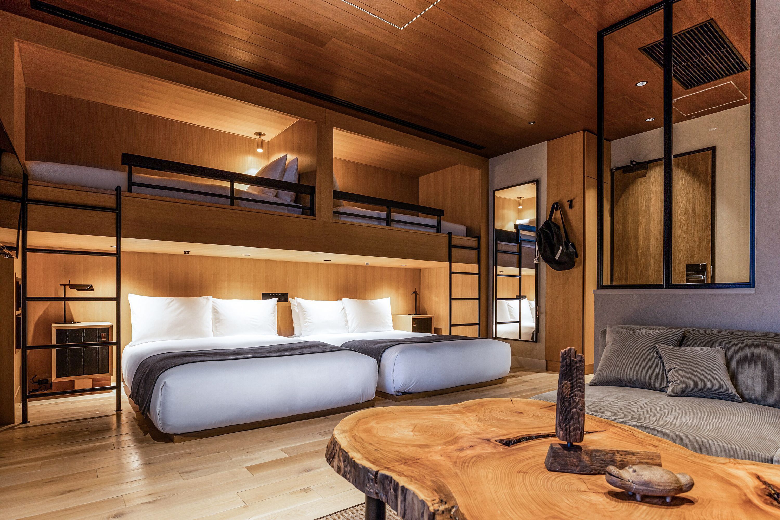 Scandinavian-styled room with wooden floor and walls, clean lines, two queen-sized beds and two loft beds.