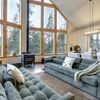 The interior of a Vrbo with huge windows looking onto a forest, with two giant sofas facing each other