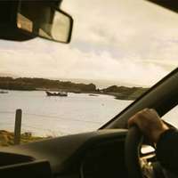 A view of islands, boats and the sea from a car driving Ireland's Wild Atlantic Way
