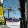 People ski beneath a chairlift on a clear day with blue skies in the French Alps