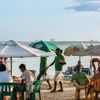 Snacks are served to guests relaxing under green and white umbrellas on the beach