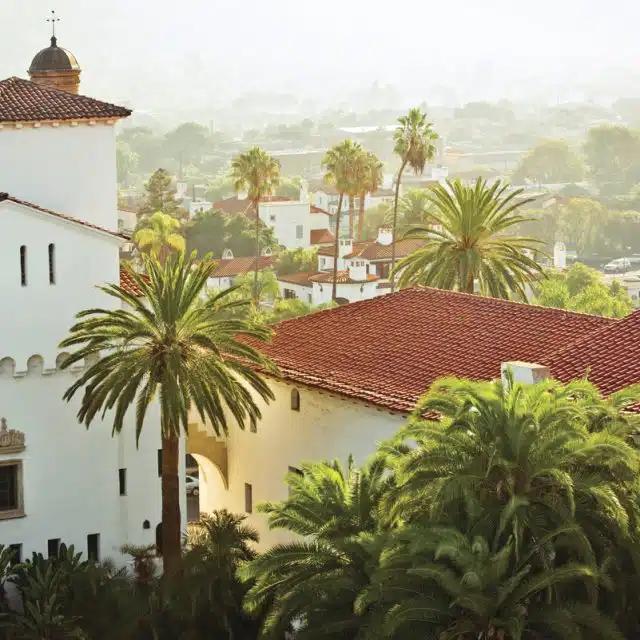 Palm trees and terracotta-roofed white buildings are seen from above in Santa Barbara, California