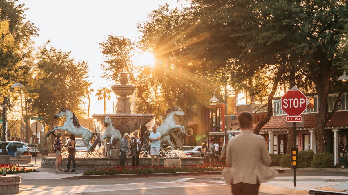 Visitors gather around a horse fountain in Old Town Scottsdale as the sun sets.