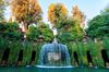 The Oval Fountain at Villa d'Este in Tivoli surrounded by green vines and trees.