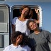 Surfer Chelsea Woody with Danielle Black Lyons and Martina Duran, smiling at the door to an RV