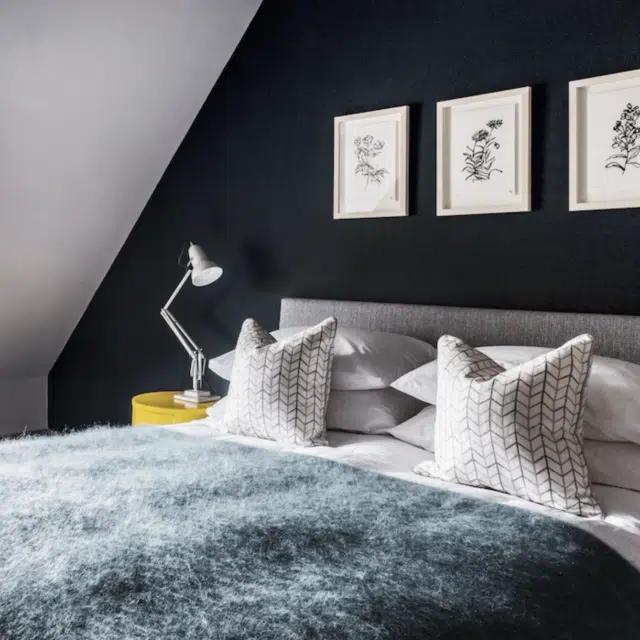 A bed in an attic room covered with a furry blue bedspread