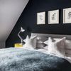 A bed in an attic room covered with a furry blue bedspread