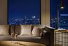 Two Champagne glasses sit on a coffee table in front of a couch with views of Tokyo at night in the background.