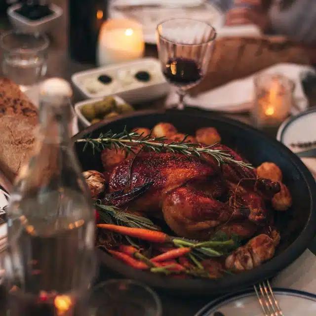 A roast turkey with herbs and carrots on a crowded dining table