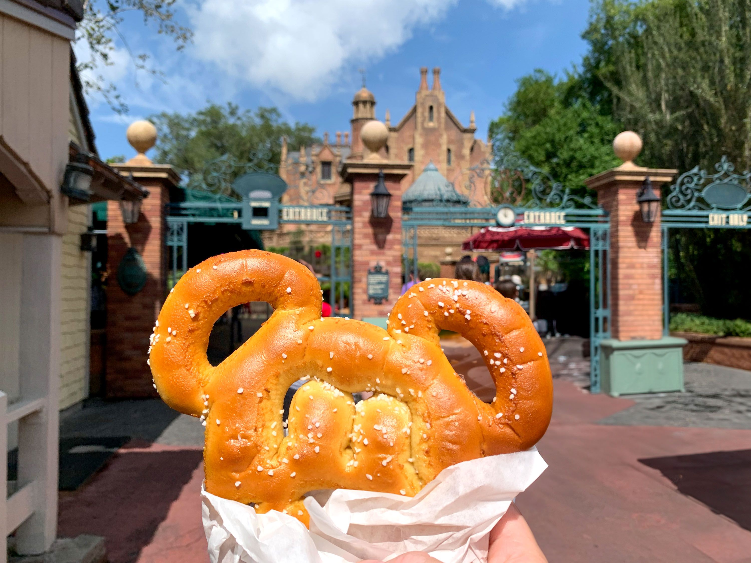 A pretzel with a shape of a head and two ears held up at an amusement park.