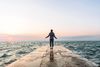 Man at the end of a concrete jetty jumps skips rope while surrounded by water.