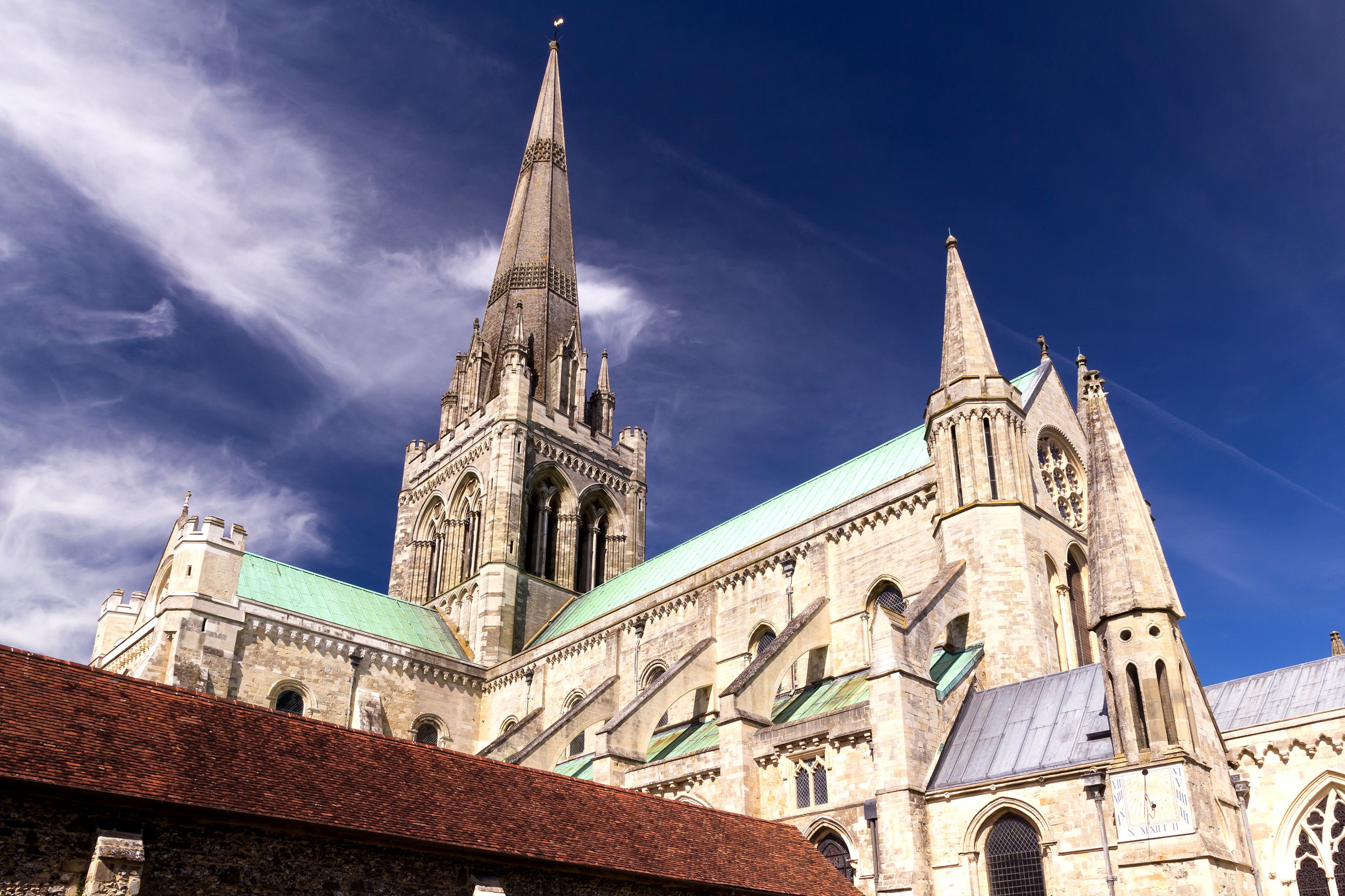 Looking up at a limestone cathedral with a green roof.