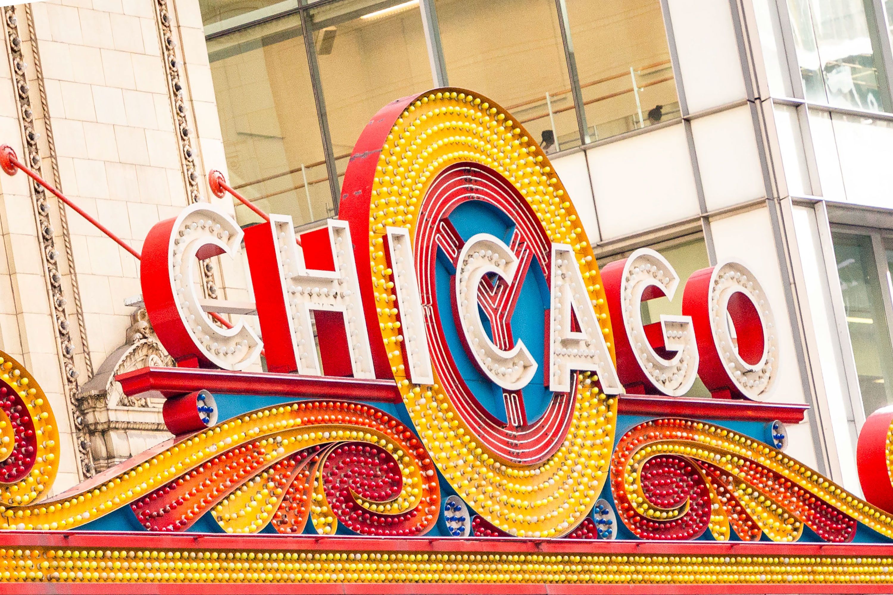 An exterior view of the Chicago Theatre featuring its illuminated Chicago marquee on a busy street in downtown Chicago.