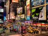 Busy street with theater signs, yellow taxi cabs and buses.