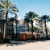 A red and yellow streetcar in New Orleans passes in the shade of palm trees