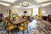 A carpeted meeting room containing a wooden table for ten and lounge area with distinct yellow chairs.