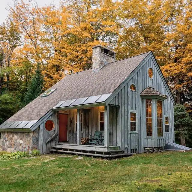 A wood cabin Vrbo with fall leaves behind in Vermont