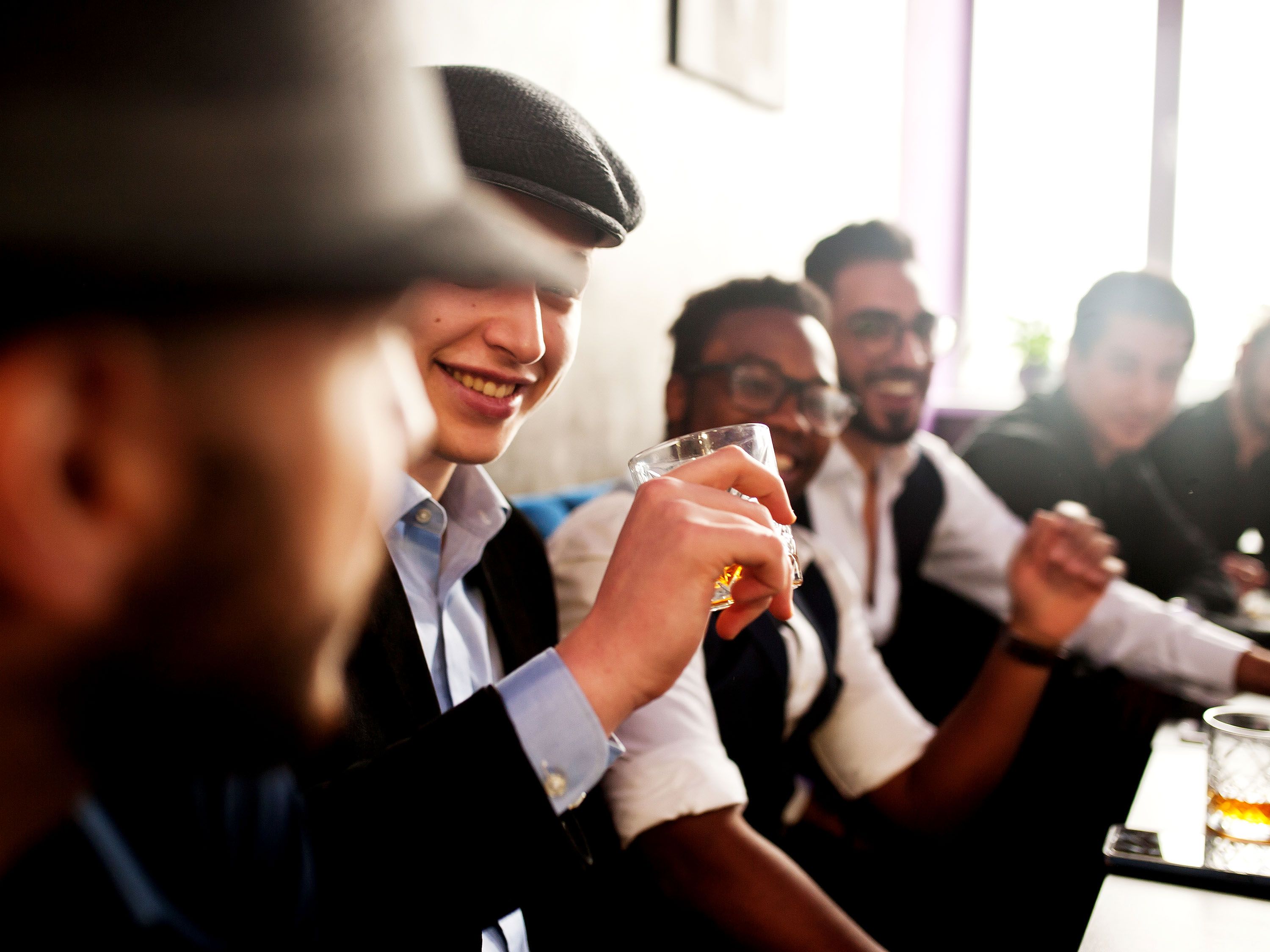Men gather at a table drinking.