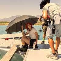 Actor Emily Rudd sits beneath an umbrella on the set of Netflix's One Piece
