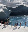 Swimmers look into a sparkling cobalt pool, surrounded by sculptural grey rocks
