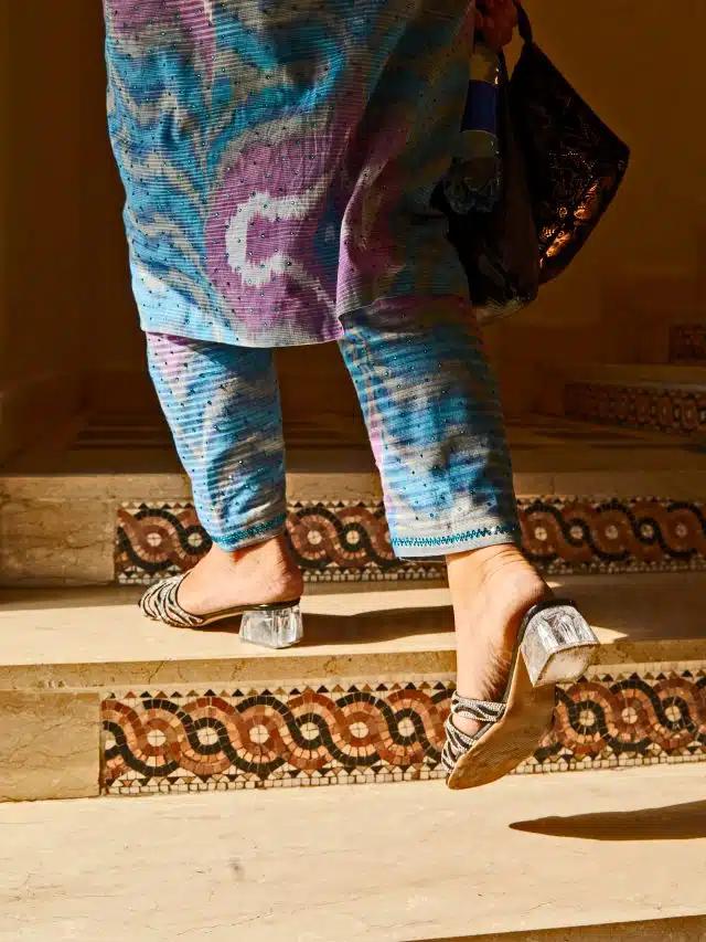 A glamorous woman climbs decorative steps at Dushanbe Bazaar, dressed in colourful clothes and silver and acetate heels