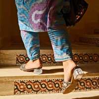A glamorous woman climbs decorative steps at Dushanbe Bazaar, dressed in colourful clothes and silver and acetate heels