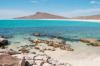 A white sandy beach and rocks along the beach and turquoise waters of Isla Espiritu Santo in Cabo San Lucas.