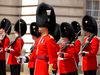 British guards with red uniforms and black hats outside Buckingham Palace.