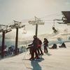 Skiers line up at the top of a snow-covered hill with a chairlift in the background