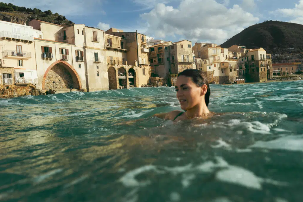 A woman swims in the sea lining the coastal city of Cefalù in Sicily