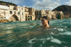 A woman swims in the sea lining the coastal city of Cefalù in Sicily