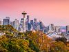 Cityscape of Seattle's Space Needle from Kerry Park with a pink sunset sky with fall colored trees in the foreground.