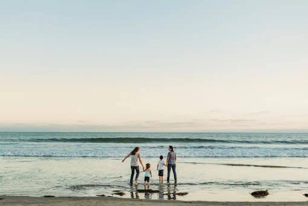 A family with two mothers and two kids paddles in the sea