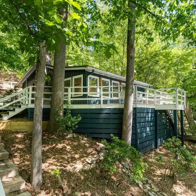 A blue and white cabin in teh woods, on the shore of Lake Lure
