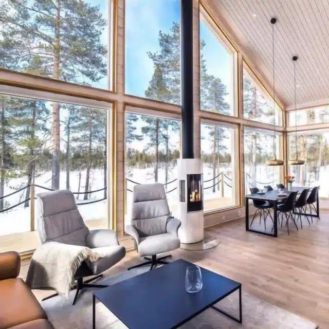 A Vrbo with vast windows looking onto a snowy forest in Finland
