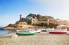 Boats on the beach with a brick wall and building behind in Spain.