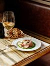 Vitello tonnato is served with a glass of wine and a bread basket in Milan, Italy