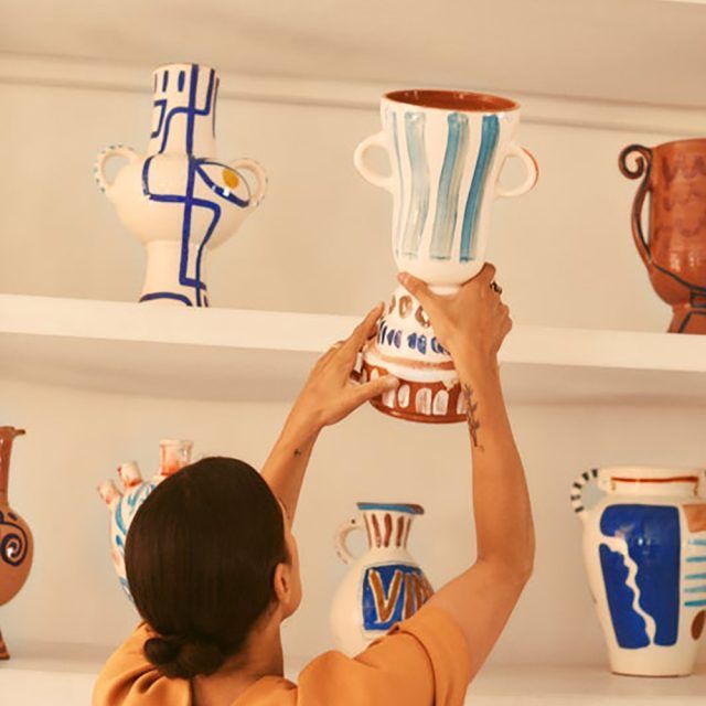 A woman picks up a handmade contemporary ceramic vase from a shelf in Morocco