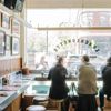 The interior of a restaurant in Chicago, with blue counters wrapping round the walls and window, and diners looking out at the sunny street