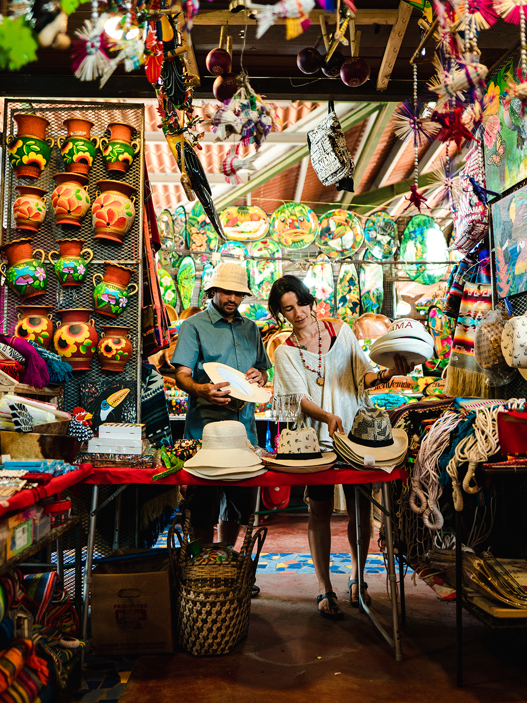Two people look at hats inside a Panamanian market filled with trinkets