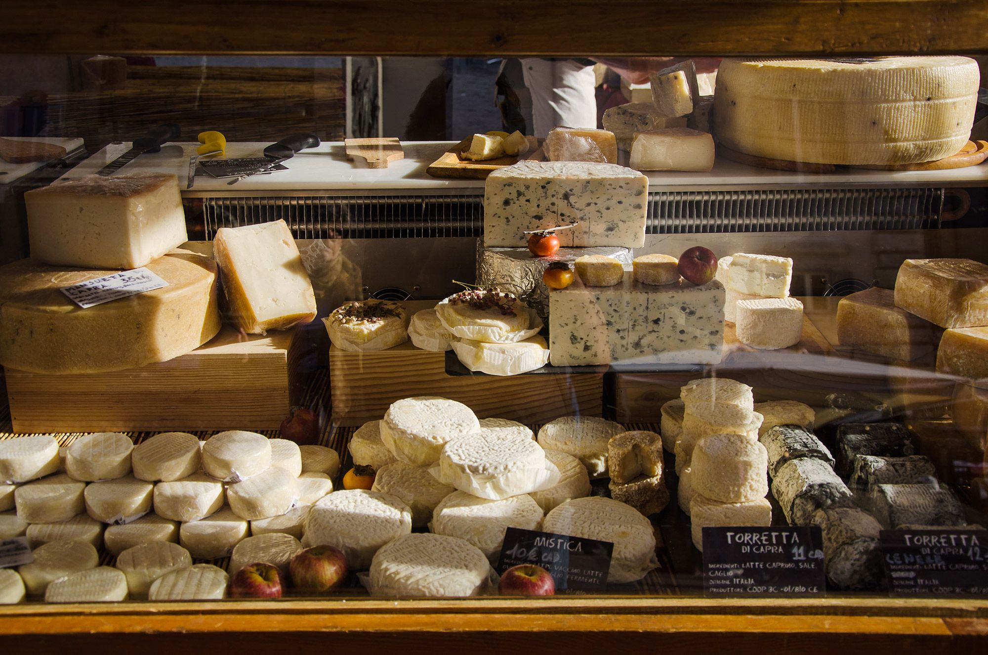 A stack of cheese sitting in a window for sale at Rome's Campo di Fiori's open air market.