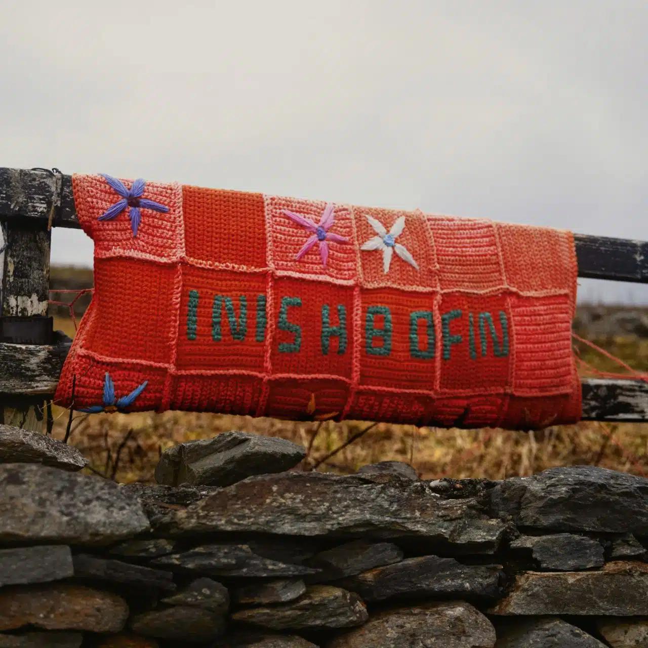 A hand-knitted patchwork sign reads Inishbofin