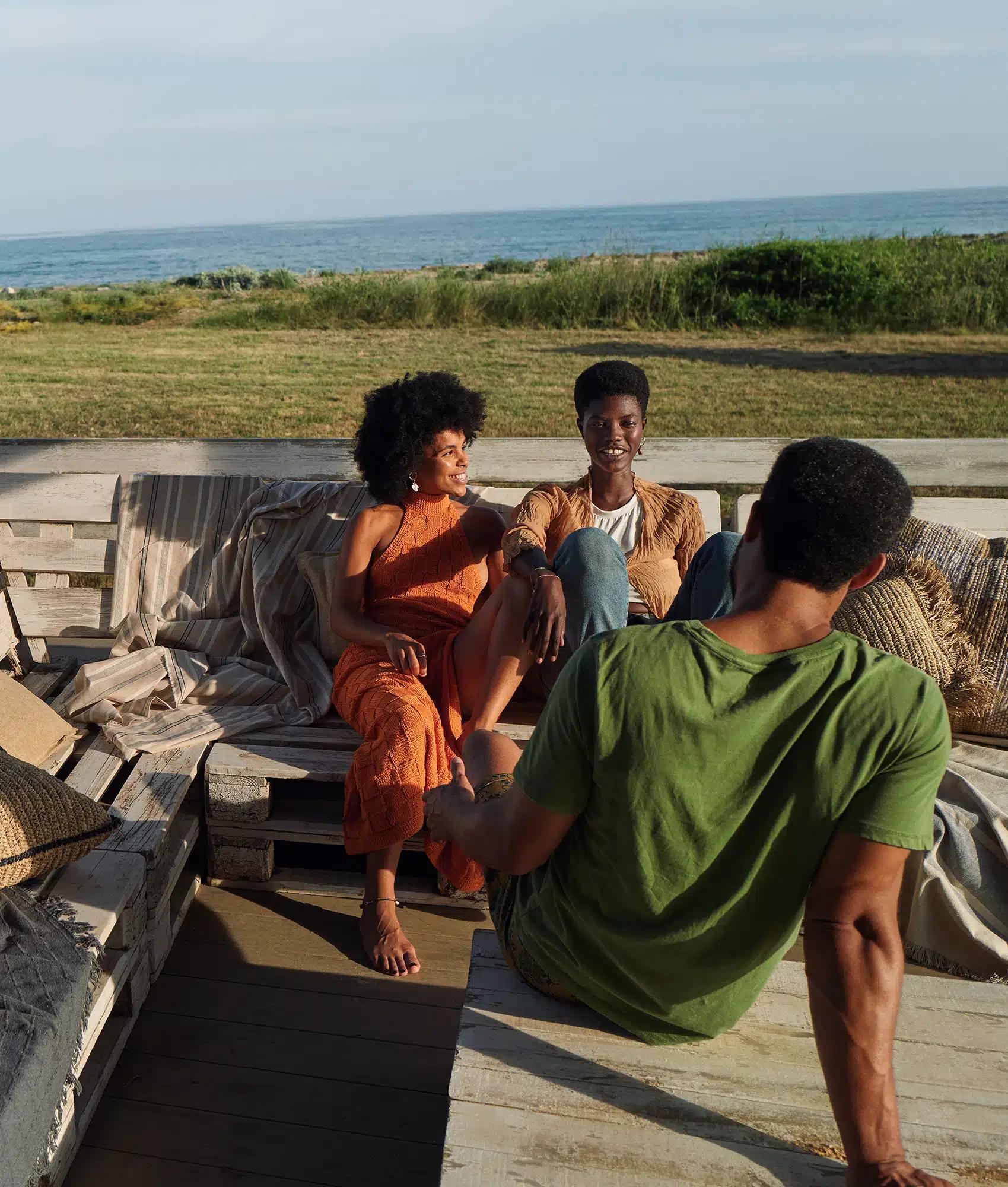 Three friends lounge on wooden garden furniture at a holiday rental property