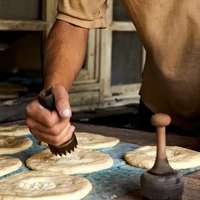 A bread maker in Dushanbe, Tajikistan, uses a hand-held stamp to put an impression of dots in the center of circles of dough