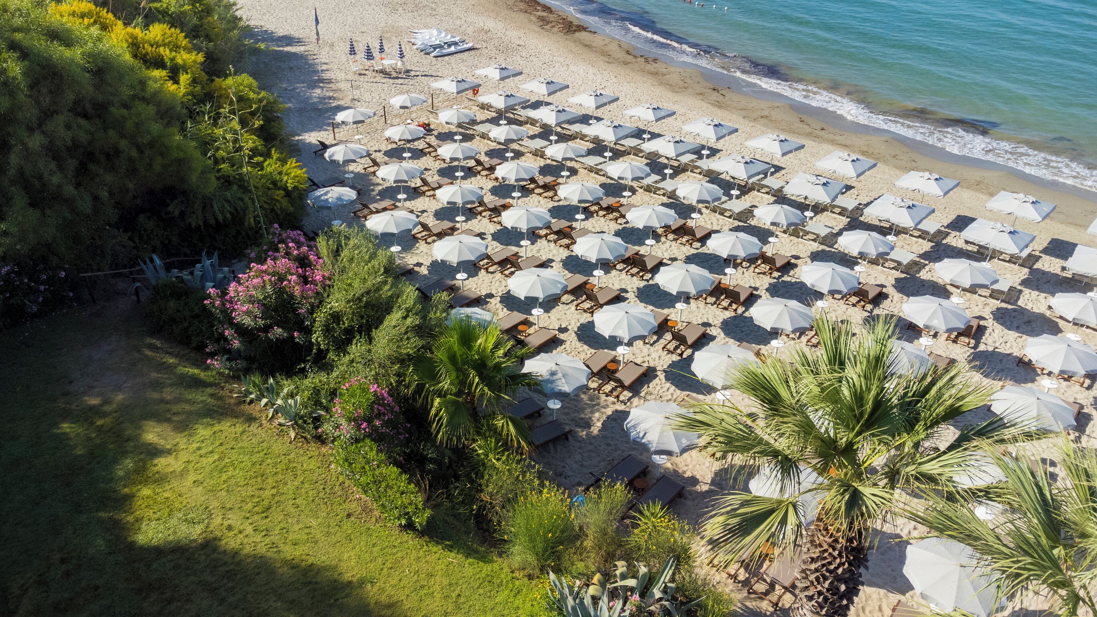 A Sicilian beach with parasols and deck chairs at Mangia's Torre del Barone Resort & Spa in Sicily