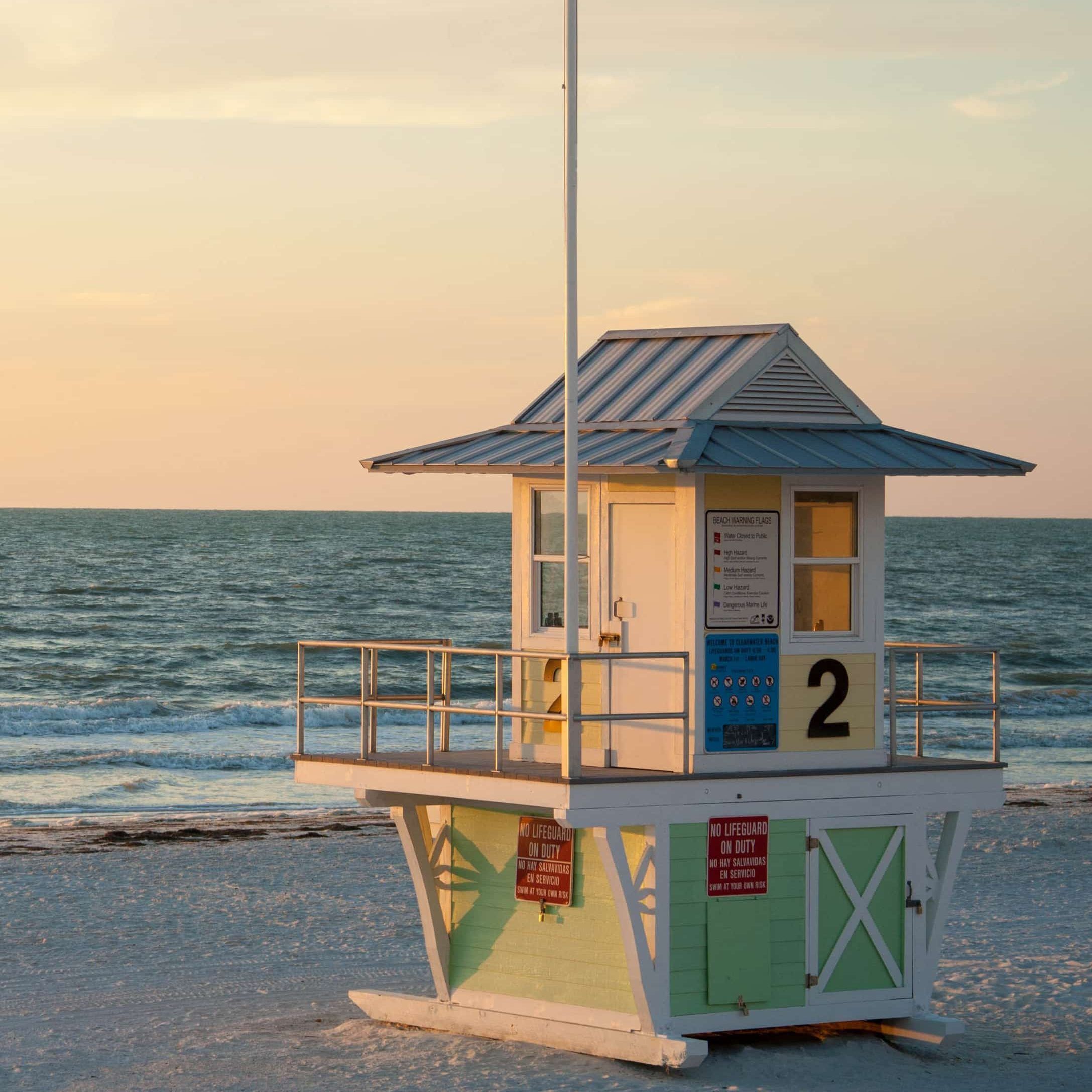 A colorful lifeguard hut on the beach at dusk, a calm sea beyond, in Tampa, Florida