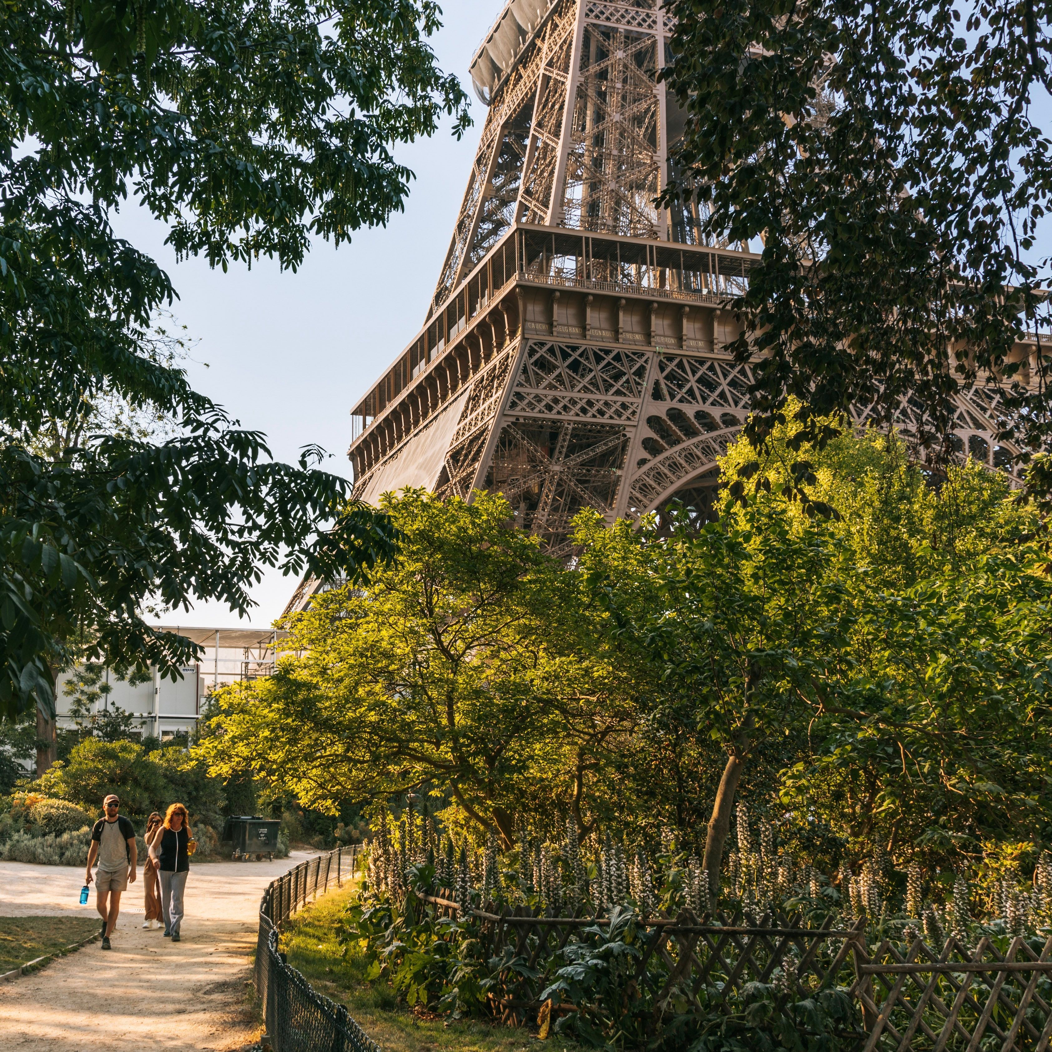 People walk along the tree-lined paths next to the Eiffel Tower in Paris, France